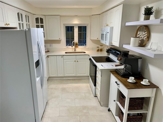 kitchen featuring white appliances, white cabinets, sink, and light tile patterned floors