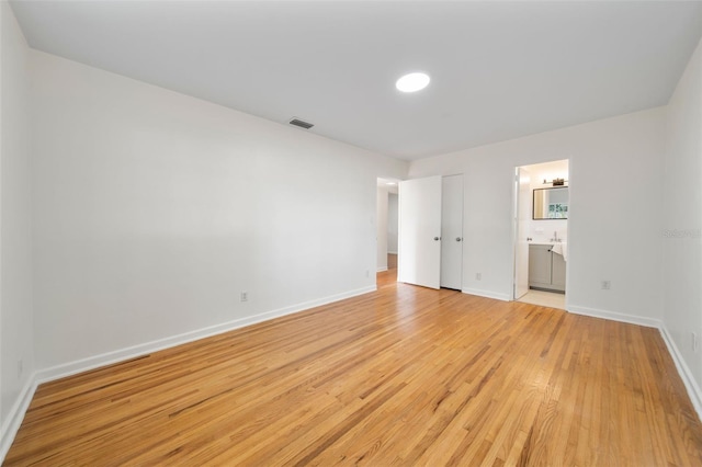 unfurnished bedroom with light hardwood / wood-style floors and ensuite bathroom