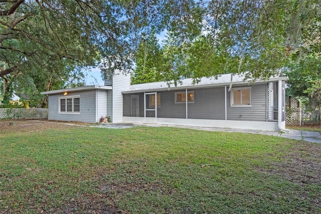 rear view of property featuring a yard and a sunroom