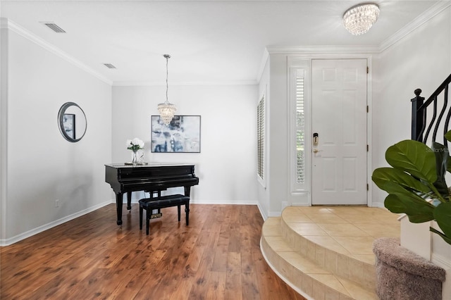 entryway with a chandelier, crown molding, and light hardwood / wood-style floors