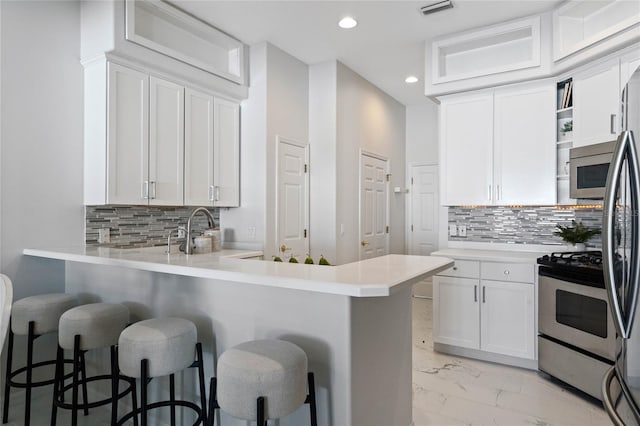 kitchen with decorative backsplash, a breakfast bar, white cabinets, and kitchen peninsula