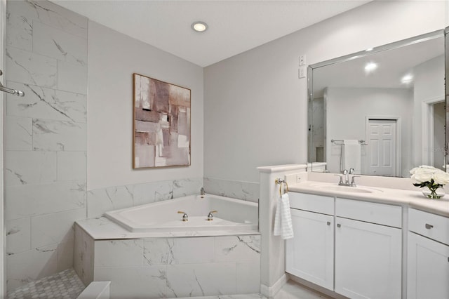 bathroom featuring tiled tub and vanity