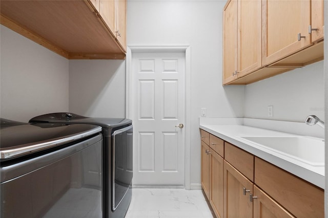 laundry room featuring sink, washing machine and clothes dryer, and cabinets