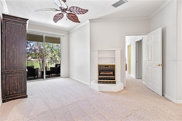 unfurnished living room featuring ceiling fan, a textured ceiling, crown molding, and light carpet