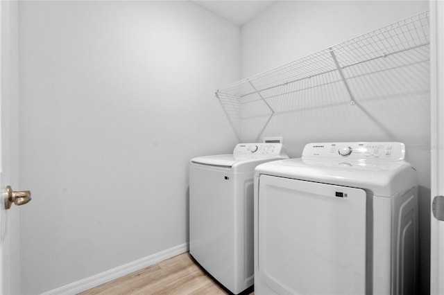 washroom with washing machine and dryer and light hardwood / wood-style floors