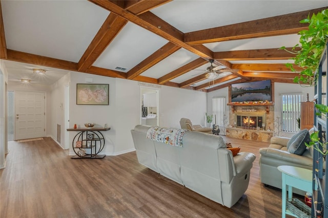 living room with hardwood / wood-style floors, ceiling fan, a stone fireplace, and lofted ceiling with beams