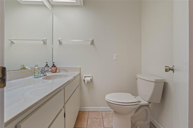 bathroom with toilet, vanity, a skylight, and tile patterned floors