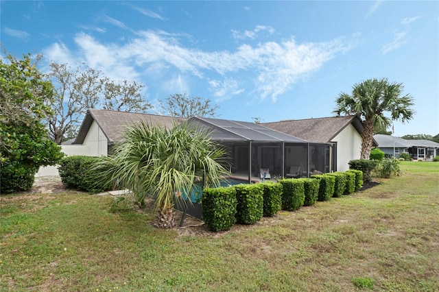 back of property featuring glass enclosure and a yard