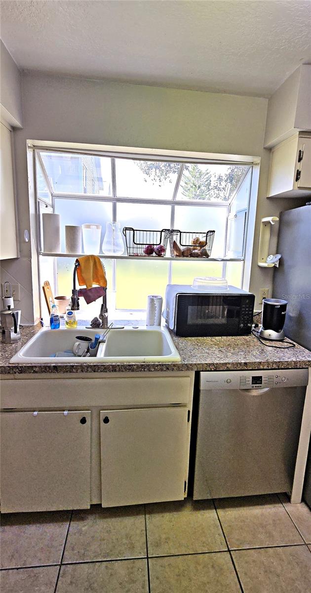 kitchen with dishwasher, light tile patterned floors, and a textured ceiling