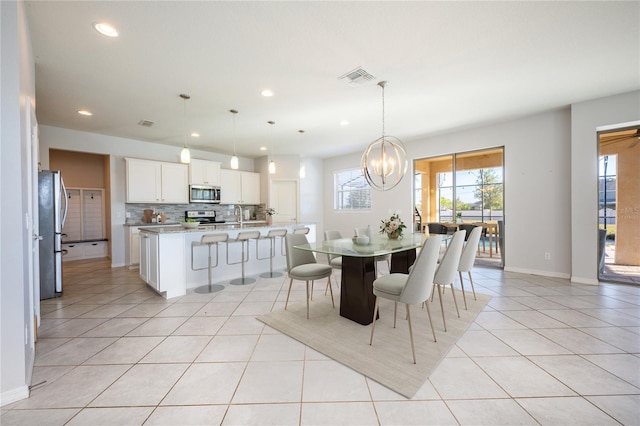 dining space featuring light tile patterned flooring, sink, and a chandelier