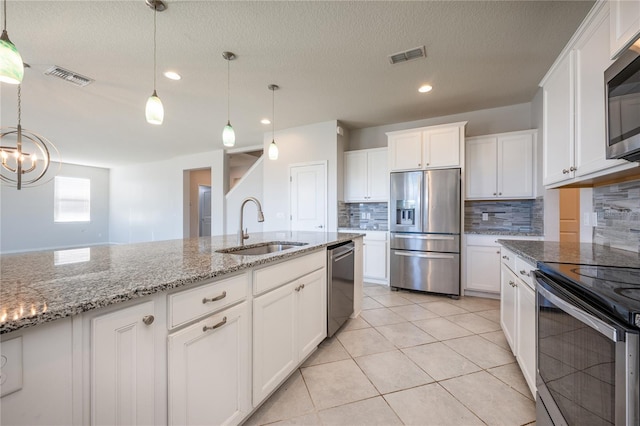 kitchen featuring white cabinets, appliances with stainless steel finishes, decorative light fixtures, and sink