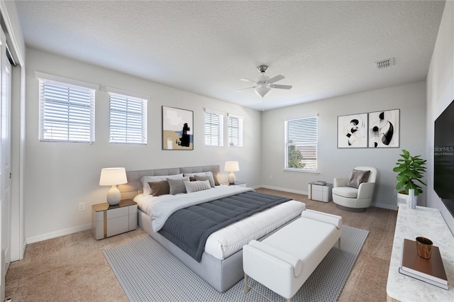 bedroom with carpet flooring, ceiling fan, a closet, and a textured ceiling