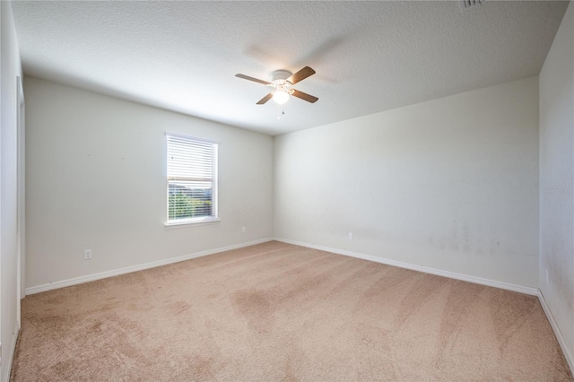 empty room featuring ceiling fan, light colored carpet, and a textured ceiling