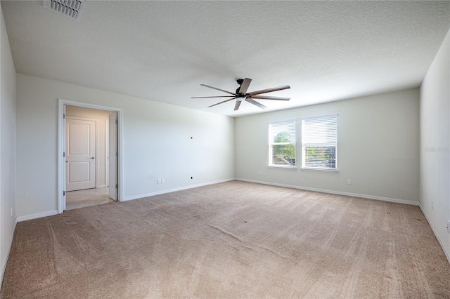 empty room with ceiling fan, light colored carpet, and a textured ceiling