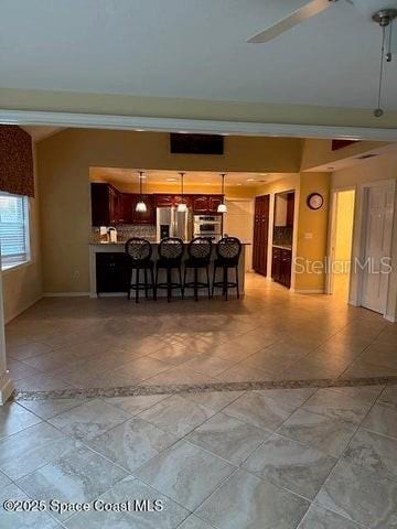 interior space with a breakfast bar area, tasteful backsplash, appliances with stainless steel finishes, kitchen peninsula, and pendant lighting