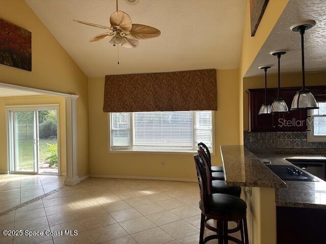 kitchen with decorative light fixtures, plenty of natural light, a kitchen breakfast bar, and light tile patterned flooring