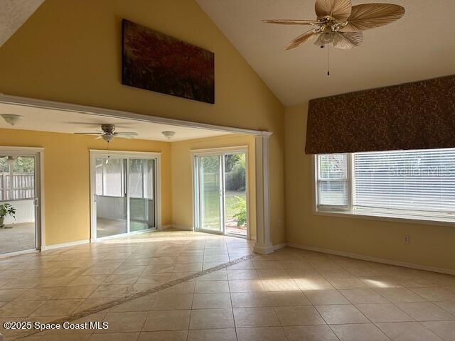 tiled empty room with ceiling fan, a healthy amount of sunlight, and lofted ceiling