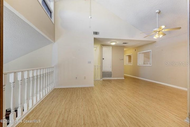 unfurnished room with ceiling fan, high vaulted ceiling, light hardwood / wood-style flooring, and a textured ceiling