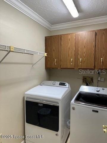 washroom with cabinets, ornamental molding, washing machine and clothes dryer, and a textured ceiling