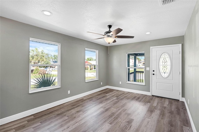 foyer entrance with ceiling fan, wood-type flooring, and a textured ceiling