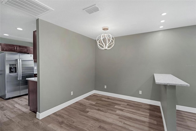 unfurnished dining area featuring a chandelier and light hardwood / wood-style flooring