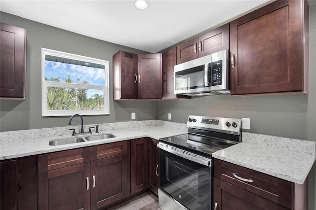 kitchen featuring light hardwood / wood-style flooring, sink, light stone counters, and stainless steel appliances