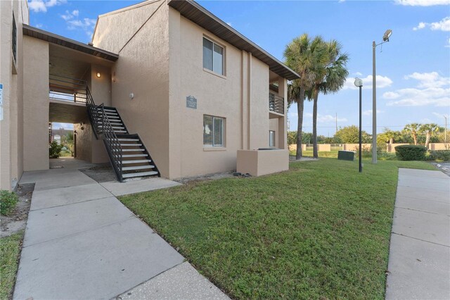 5208 Via Hacienda Cir Unit 201, Orlando, FL 32839 - view of property exterior with stairs, stucco siding, and a yard