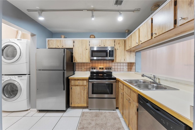 kitchen with sink, stacked washer / drying machine, appliances with stainless steel finishes, light brown cabinets, and light tile patterned floors