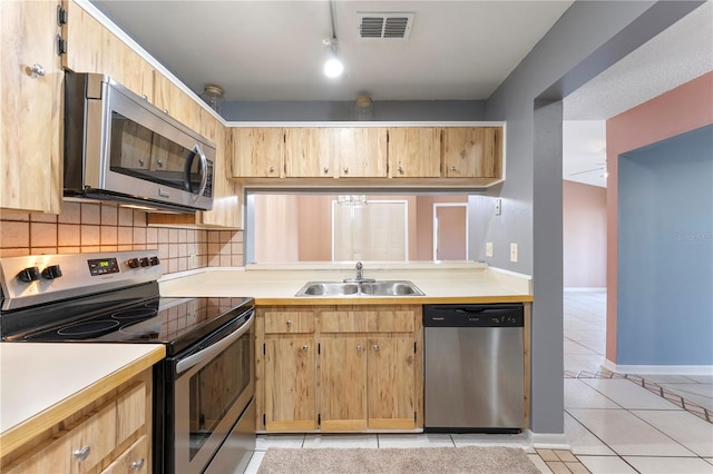 kitchen featuring appliances with stainless steel finishes, track lighting, light tile patterned floors, decorative backsplash, and sink