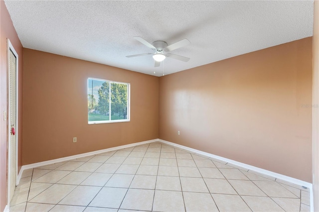 empty room with a textured ceiling, ceiling fan, and light tile patterned floors