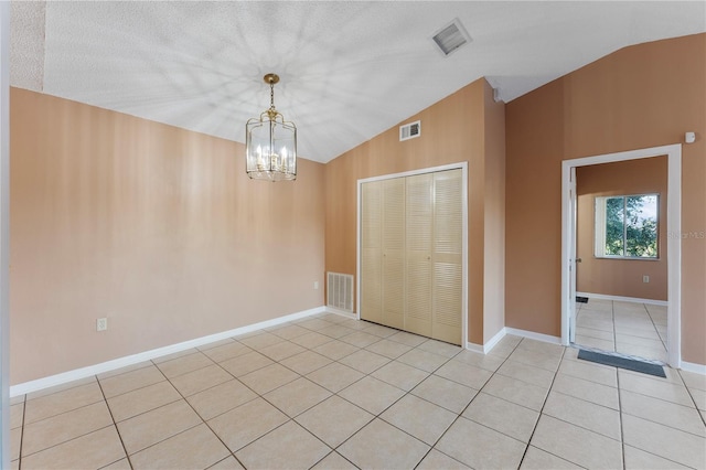 interior space with a closet, lofted ceiling, a textured ceiling, and a notable chandelier