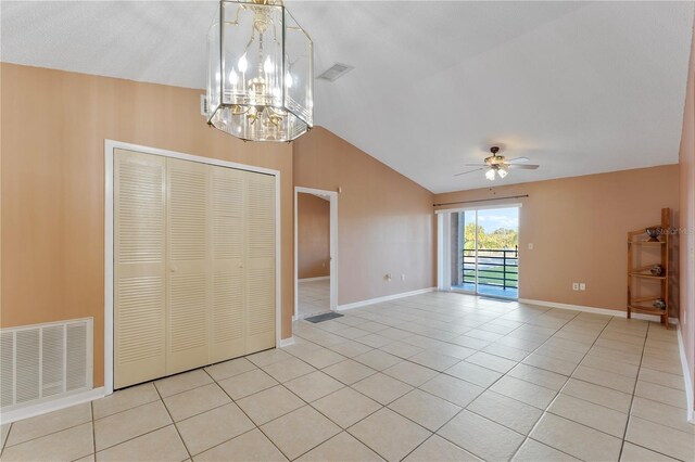 spare room featuring vaulted ceiling, light tile patterned flooring, and ceiling fan with notable chandelier