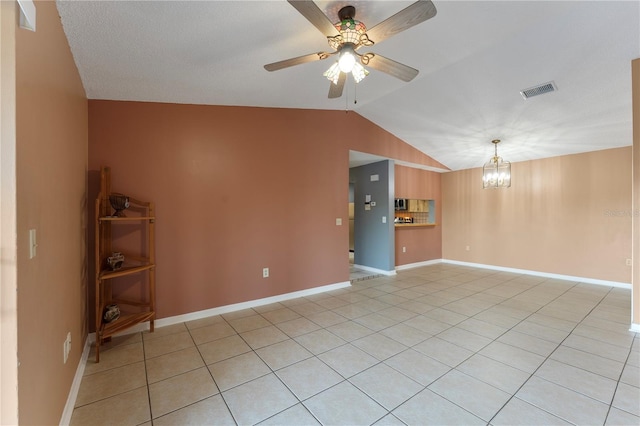 tiled spare room with ceiling fan with notable chandelier and lofted ceiling