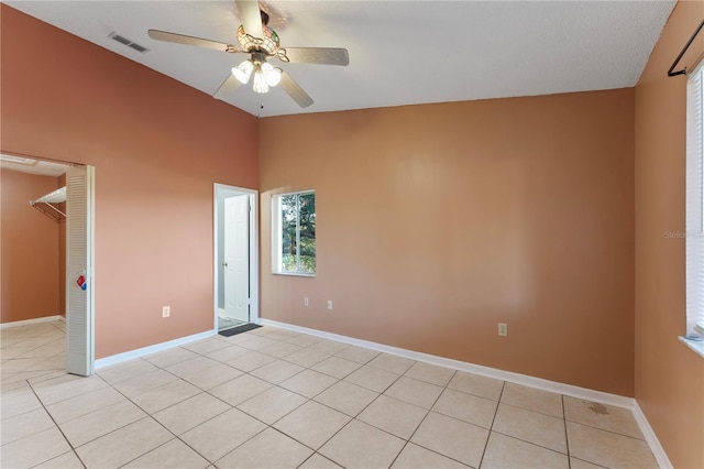 unfurnished room with ceiling fan, a textured ceiling, light tile patterned floors, and vaulted ceiling