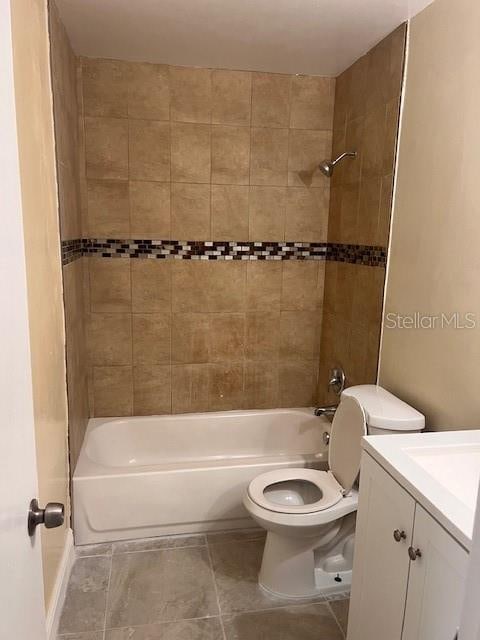 full bathroom featuring tile patterned floors, vanity, tiled shower / bath combo, and toilet