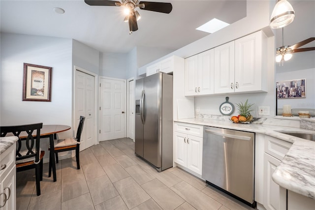 kitchen featuring sink, ceiling fan, appliances with stainless steel finishes, light stone counters, and white cabinetry