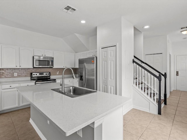 kitchen with sink, white cabinetry, stainless steel appliances, and a kitchen island with sink