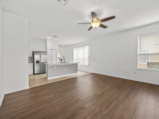 unfurnished living room featuring ceiling fan, plenty of natural light, light hardwood / wood-style floors, and sink