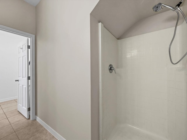 bathroom with tile patterned floors, vaulted ceiling, and a tile shower