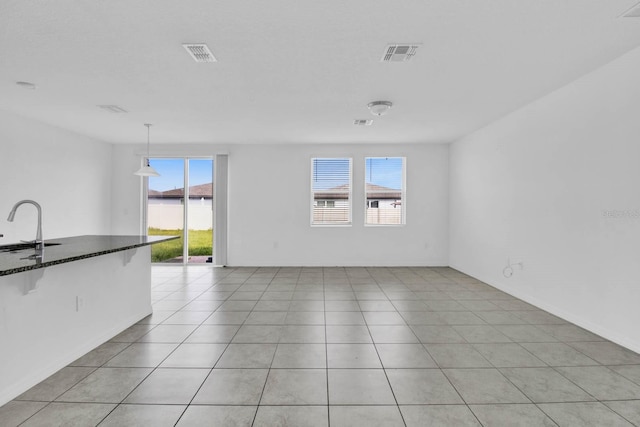 tiled spare room featuring a healthy amount of sunlight and sink