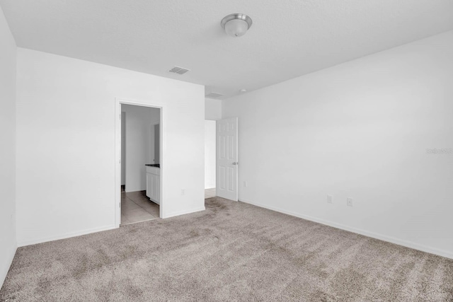 unfurnished bedroom with ensuite bath and light colored carpet