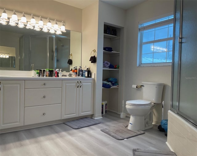 bathroom with built in features, walk in shower, vanity, hardwood / wood-style flooring, and toilet