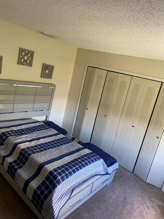 bedroom with carpet flooring, a textured ceiling, and a closet