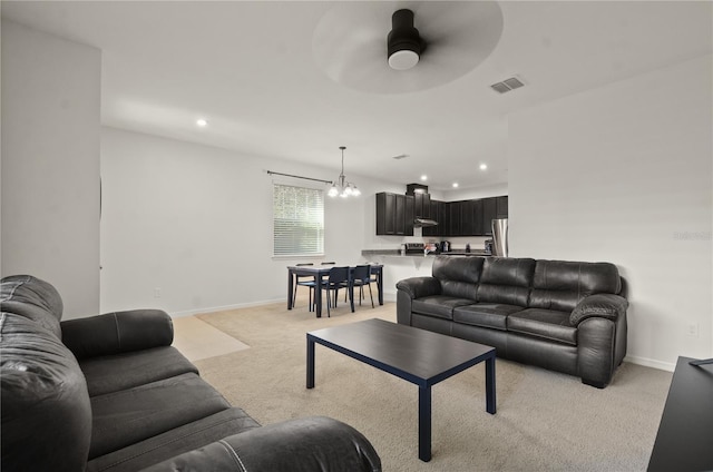 carpeted living room featuring ceiling fan with notable chandelier