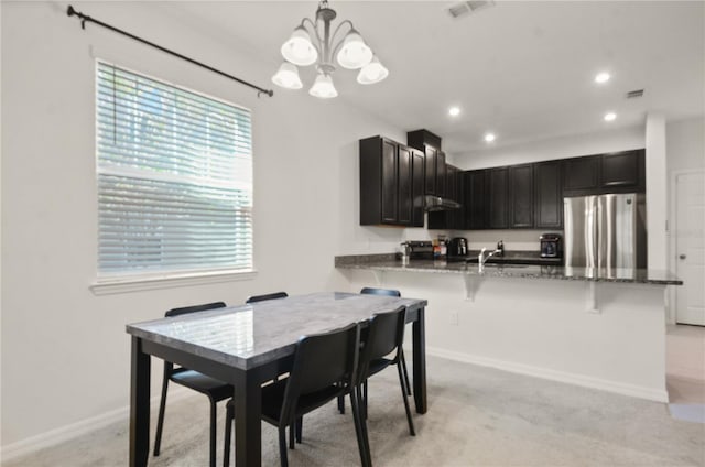 carpeted dining area featuring sink and a notable chandelier