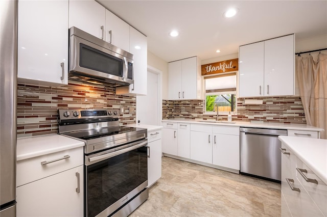 kitchen featuring appliances with stainless steel finishes, backsplash, white cabinetry, and sink