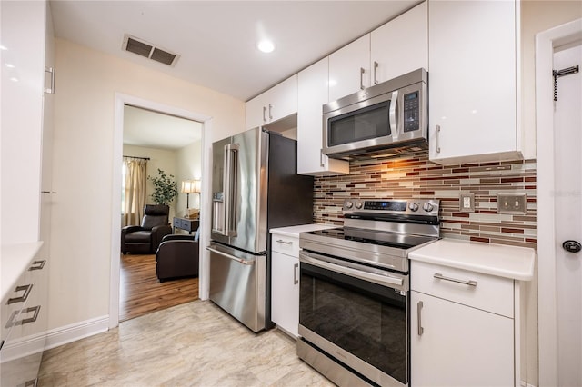 kitchen featuring decorative backsplash, white cabinets, stainless steel appliances, and light wood-type flooring