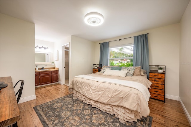 bedroom featuring ensuite bathroom, sink, and hardwood / wood-style flooring