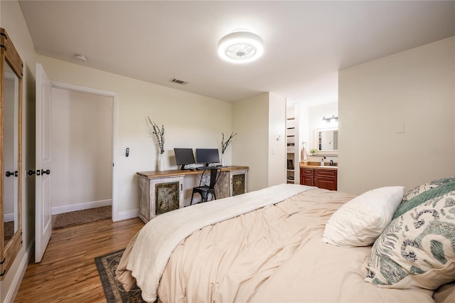 bedroom with connected bathroom and hardwood / wood-style flooring