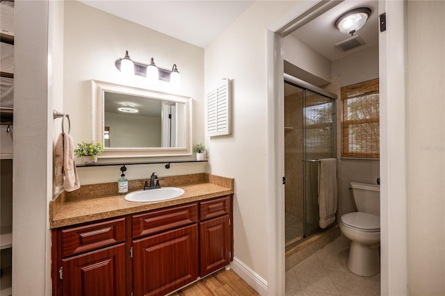 bathroom with tile patterned flooring, vanity, toilet, and a shower with door